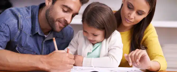 parents working with kid on homework at table together
